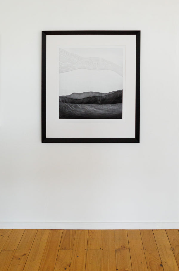 An in room image showing limited edition photographic print featuring abstract representations of a landscape, with cultural references with a black wedge frame.