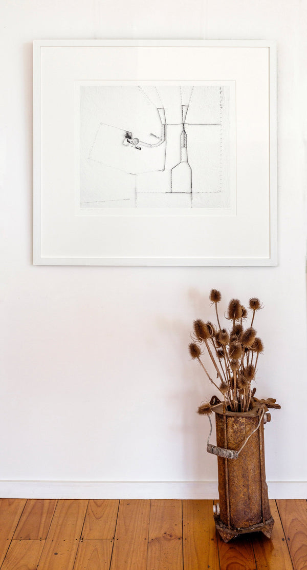 Framed black and white artwork on a white wall with a wooden floor.
