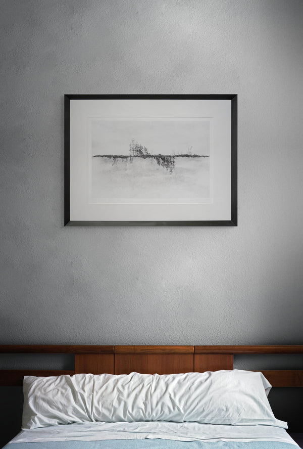 Framed black and white artwork on a gray wall above a bed with wooden headboard.