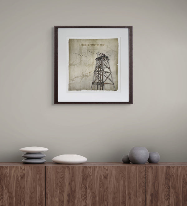 Framed architectural drawing on a wall above a wooden cabinet with decorative items.