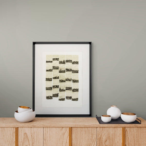 Framed artwork on a wooden shelf with decorative bowls against a gray wall