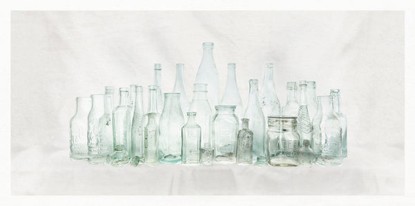 Collection of various vintage glass bottles on a light background