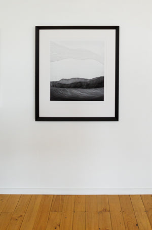 An in room image showing  limited edition  photographic print featuring abstract representations of a landscape, with cultural references with a black wedge frame.