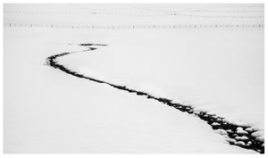 Creek bed leading into a snowy landscape