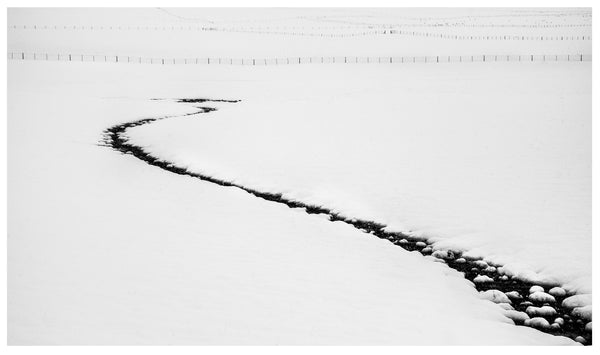Creek bed leading into a snowy landscape