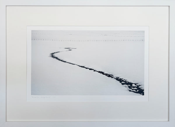 Framed black and white photograph of a snowy landscape with a curved creek bed.