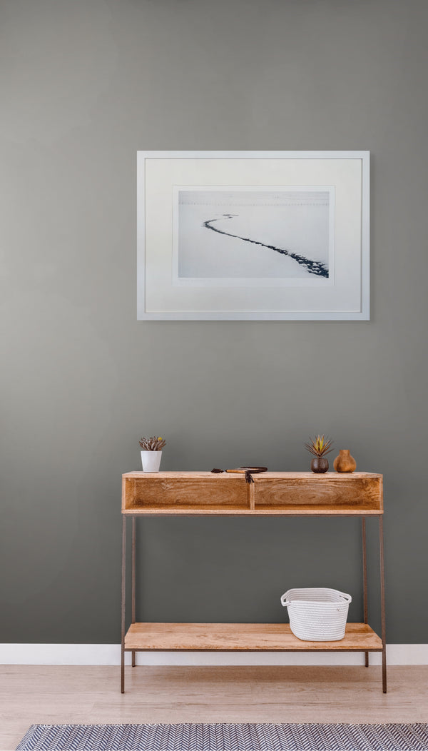 Wooden console table against a gray wall with a framed picture above it.